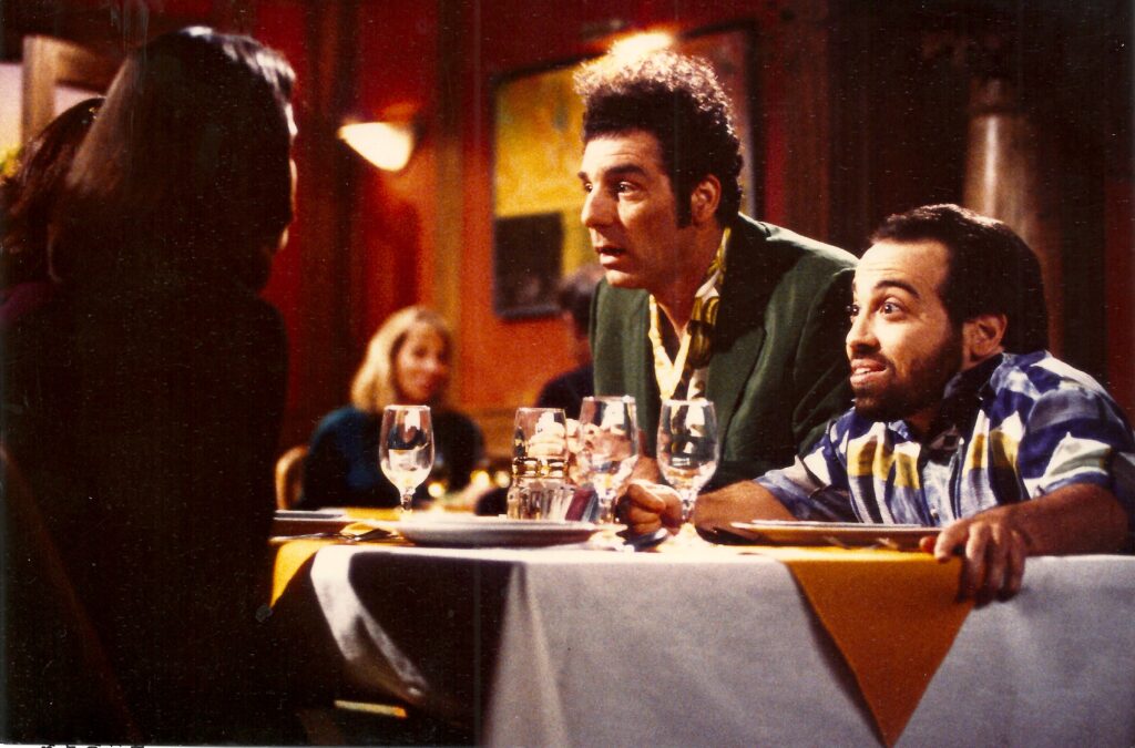 Studio shot of Danny as Mickey Abbot from Seinfeld (Yada Yada episode) at dinner double date with Kramer looking excitedly at dates.