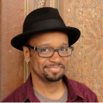 African American man with goatee and glasses, wearing a hat.