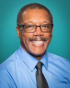 African american man wearing glasses and blue shirt, smiles at the camera.
