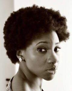 A headshot of Black woman who has an afro.